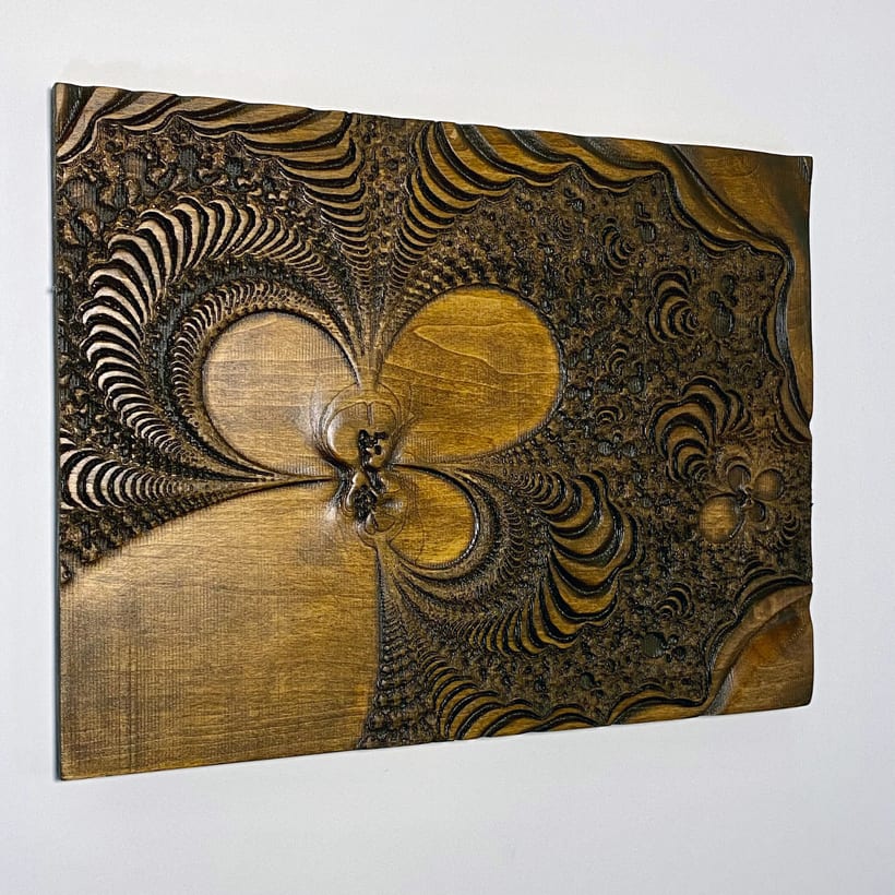 Detail of a CNC-carved Mandelbrot set in wood, showing the scalloped surface left by a 1/16 inch ball nose finishing pass