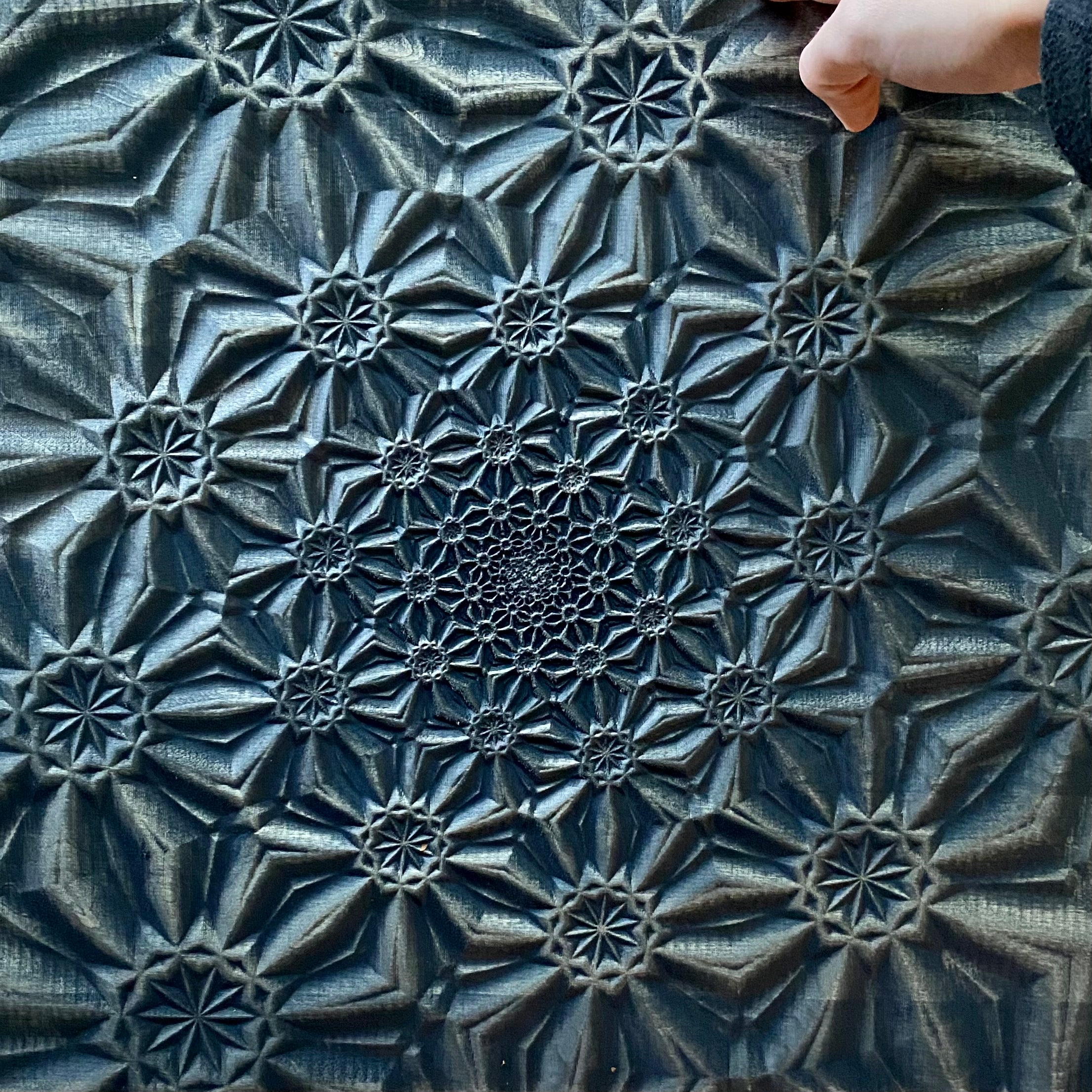 Detail view of logarithmic spiral wood carving showing dimensional depth and grain pattern